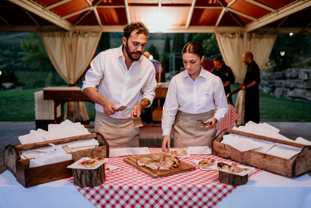 Twee pizzabakkers serveren de pizza uit op de vooravond van een bruiloft in toscane